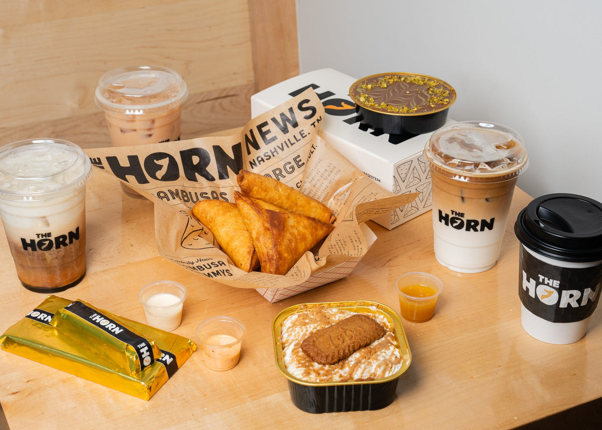 Sambusas in The Horn deli paper next to hot and iced Horn chai