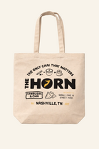 Beige tote bag with 'The Horn' branding and text on a white background