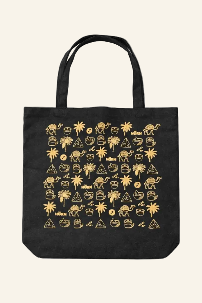 Black tote bag with gold graphic design on a white background